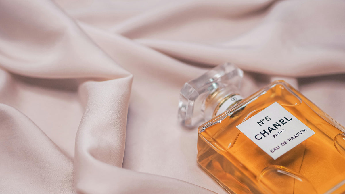 A bottle of perfume resting on pale pink silk